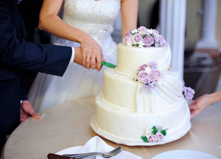 couple praying and cutting wedding cake