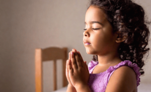 a toddler praying during bedtime